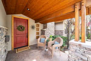 Entrance to property with stone siding, covered porch, and stucco siding