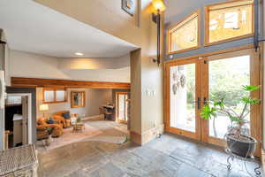 Foyer with stone tile floors, recessed lighting, french doors, and a high ceiling
