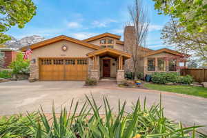 View of front facade featuring stucco siding, a garage, stone siding, and driveway