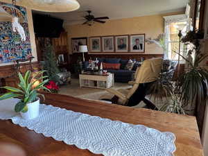 Living area with wainscoting, wooden walls, a ceiling fan, and crown molding