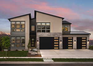 Contemporary house featuring stucco siding, concrete driveway, stone siding, a yard, and an attached garage