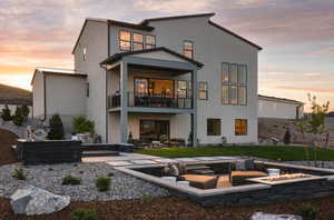 Back of property with an outdoor living space with a fire pit, a patio, a balcony, a standing seam roof, and stucco siding