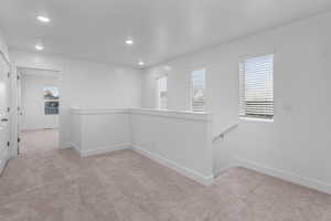 Hallway with light carpet and recessed lighting