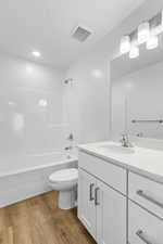 Bathroom featuring light wood-type flooring, vanity,  shower combination, and recessed lighting