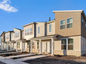 View of front of property with a porch, stone siding, and stucco siding
