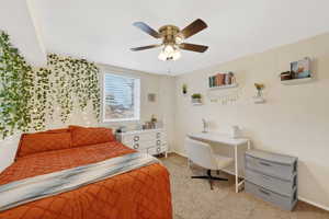 Basement apartment bedroom with light colored carpet and ceiling fan