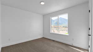 Unfurnished room with a mountain view and carpet floors