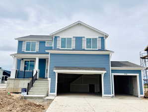 View of front facade featuring driveway, a garage, roof with shingles, and covered porch