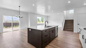Kitchen featuring dark wood finish cabinets, light wood-style floors, a chandelier, and open floor plan