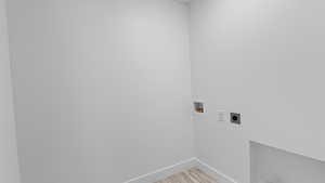 Laundry area featuring hookup for an electric dryer, hookup for a washing machine, and light wood-style flooring