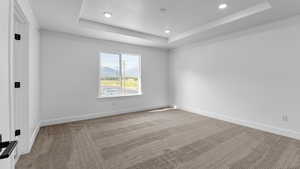 Spare room featuring a raised ceiling, carpet flooring, a mountain view, and recessed lighting