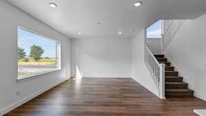 Unfurnished living room featuring dark wood-type flooring, healthy amount of natural light, recessed lighting, and a textured ceiling
