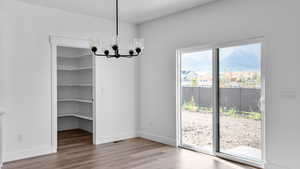 Unfurnished dining area featuring suspended lighting and light wood-type flooring