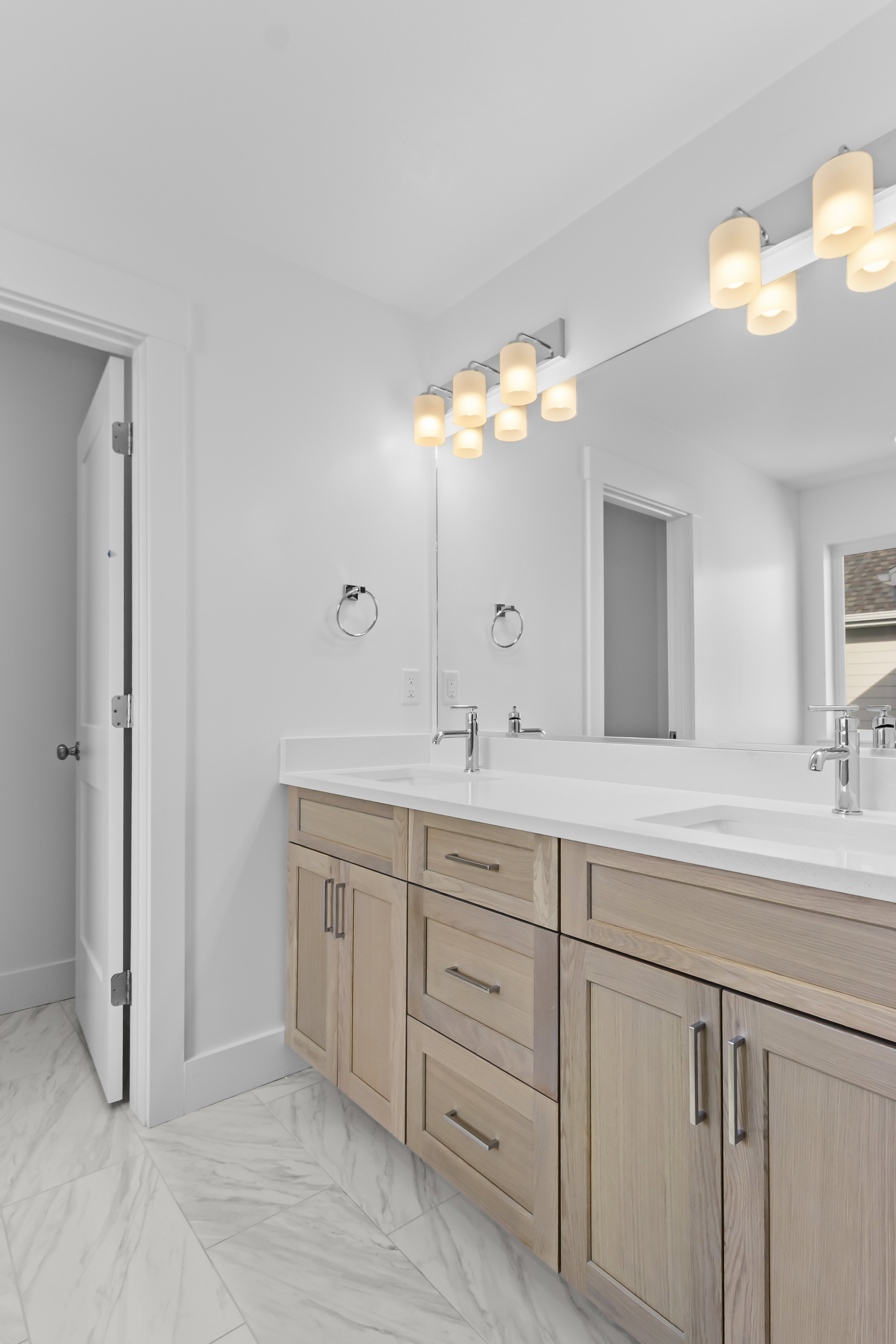 Bathroom with double vanity and light marble finish flooring