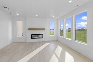 Unfurnished living room with a glass covered fireplace, light wood-style floors, and recessed lighting