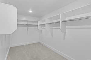 Walk in closet with light colored carpet