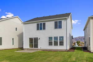 Back of property featuring a lawn, a patio, and a mountain view