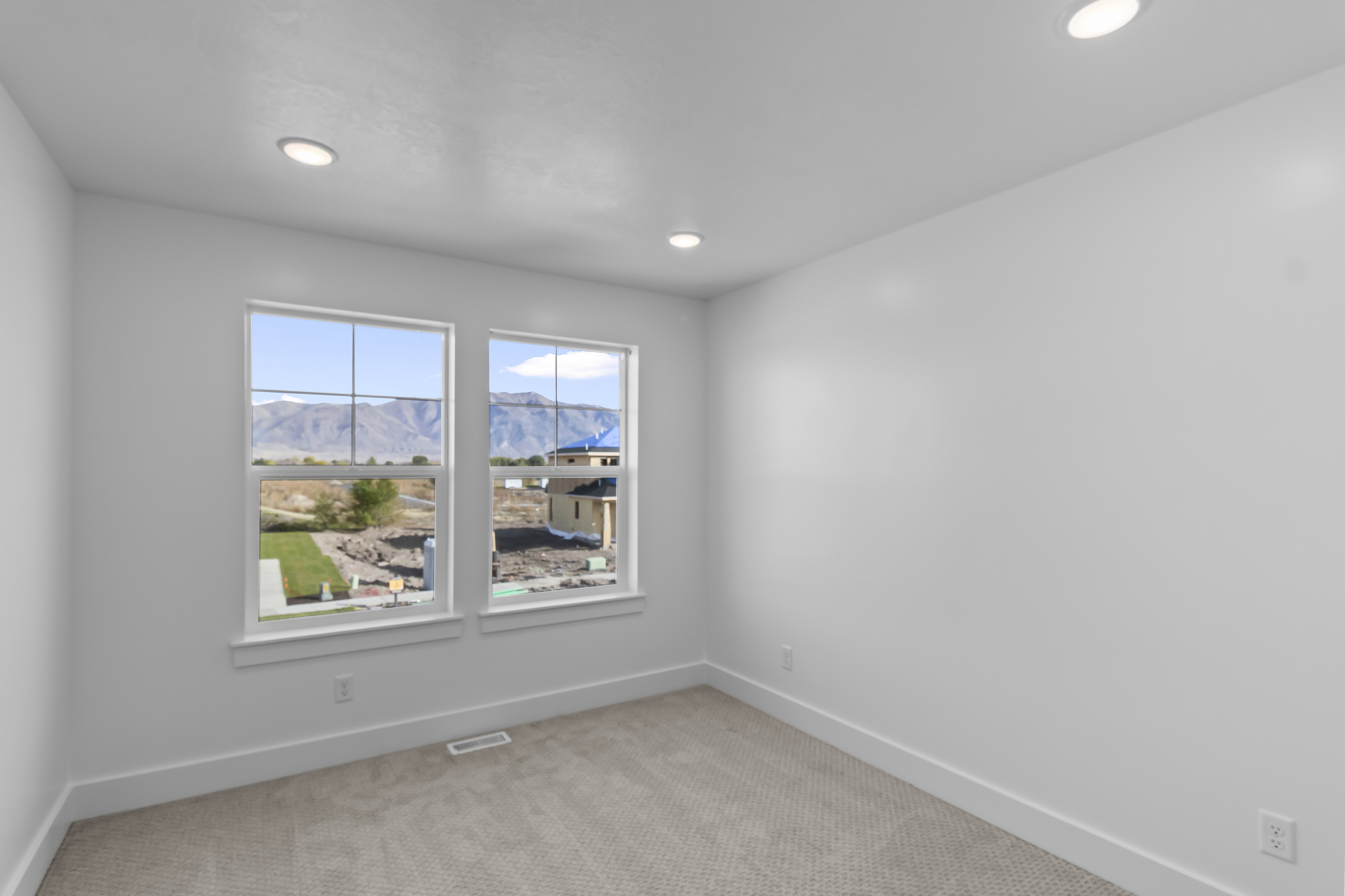 Empty room featuring light carpet, a mountain view, and recessed lighting