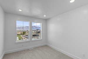 Empty room featuring light carpet, a mountain view, and recessed lighting
