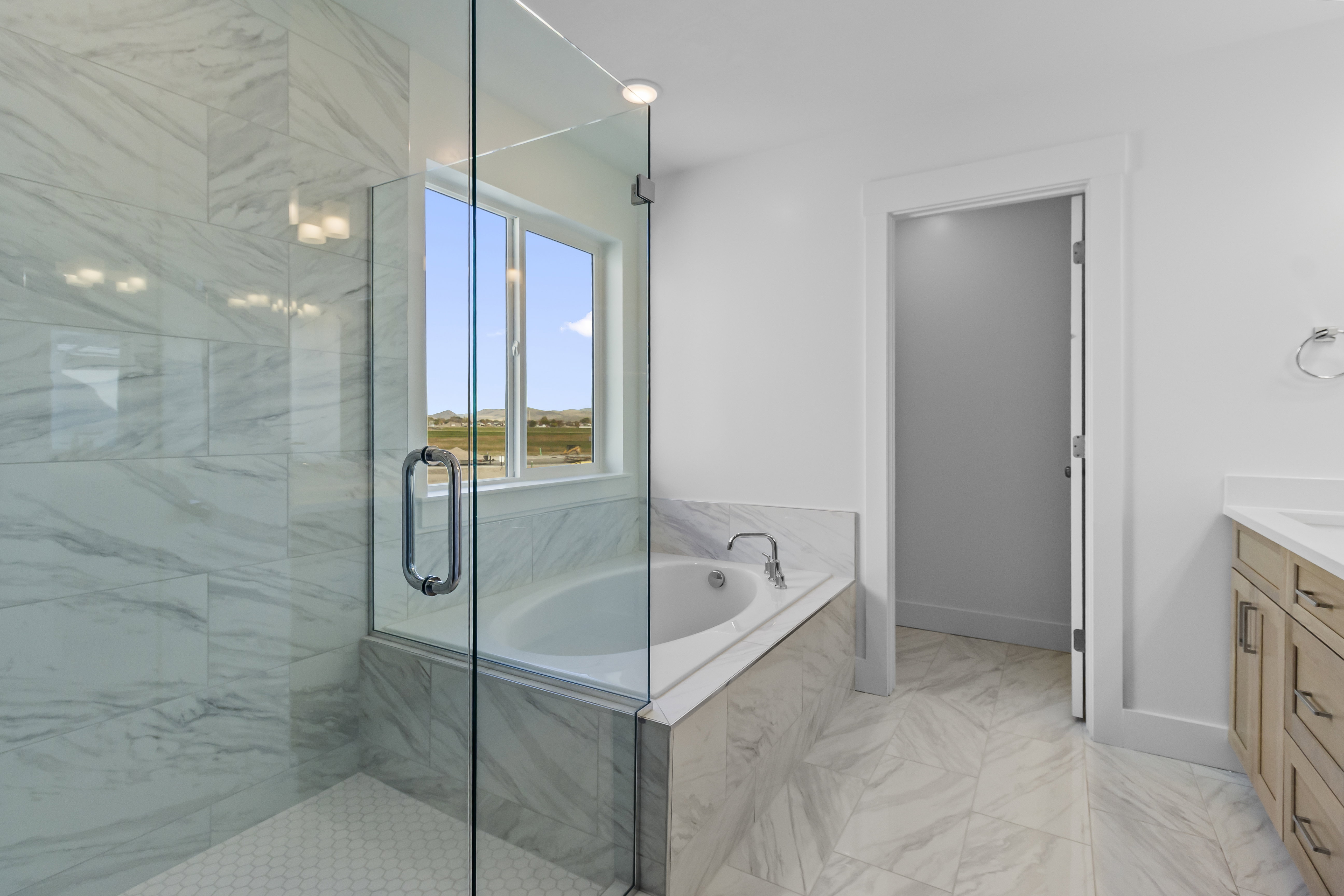 Full bath featuring vanity, a garden tub, a marble finish shower, and light marble finish flooring