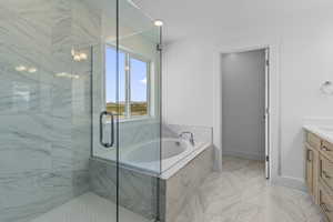 Full bath featuring vanity, a garden tub, a marble finish shower, and light marble finish flooring