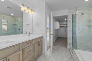 Full bath with a walk in closet, double vanity, a marble finish shower, recessed lighting, and light marble finish flooring