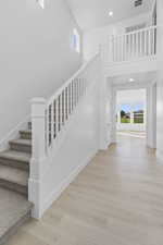 Staircase featuring wood finished floors, recessed lighting, and a high ceiling