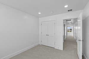 Unfurnished bedroom with light colored carpet, recessed lighting, and a closet