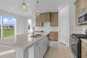 Kitchen with stainless steel appliances, light stone counters, decorative backsplash, pendant lighting, and light wood-type flooring