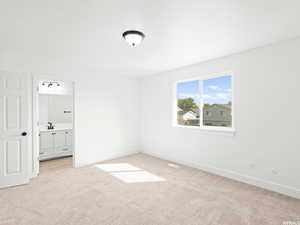 Unfurnished bedroom featuring light colored carpet and ensuite bathroom
