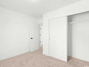 Unfurnished bedroom with light carpet and a closet