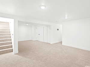Finished below grade area with stairway and light colored carpet