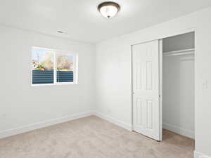 Unfurnished bedroom with light carpet and a closet