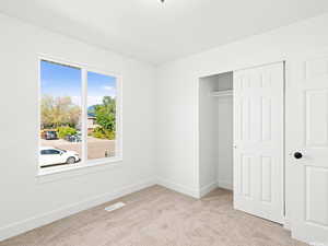 Unfurnished bedroom featuring light carpet and a closet