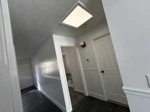 Hallway skylight with laminate vinyl plank flooring & a textured ceiling