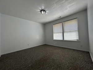 Bedroom with neutral tone carpet & textured ceiling.