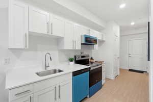 Kitchen with white cabinets, electric range, dishwashing machine, light wood finished floors, and recessed lighting
