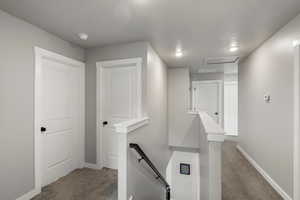 Corridor featuring an upstairs landing and carpet flooring