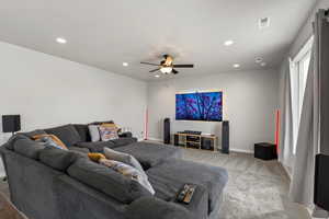 Carpeted living area with a ceiling fan and recessed lighting