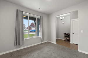 Carpeted spare room with baseboards and suspended lighting