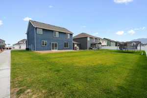 Rear view of house featuring a trampoline, a residential view, stucco siding, and a patio area