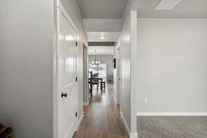 Hallway featuring a chandelier and dark wood-style floors