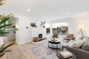 Living area featuring light wood-style flooring, a glass covered fireplace, and recessed lighting