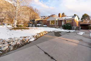 View of front of property featuring brick siding, a chimney, and concrete driveway