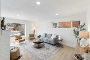 Living area featuring light wood finished floors, a textured ceiling, and recessed lighting