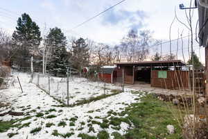 Yard covered in snow with a patio and a storage shed
