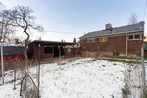 Snow covered house with brick siding and a patio