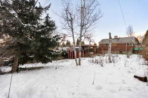 Yard layered in snow featuring a storage shed