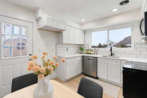 Kitchen featuring stainless steel appliances, light wood-style floors, white cabinets, light stone countertops, and recessed lighting