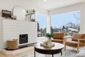 Living area featuring wood finished floors, a glass covered fireplace, and recessed lighting